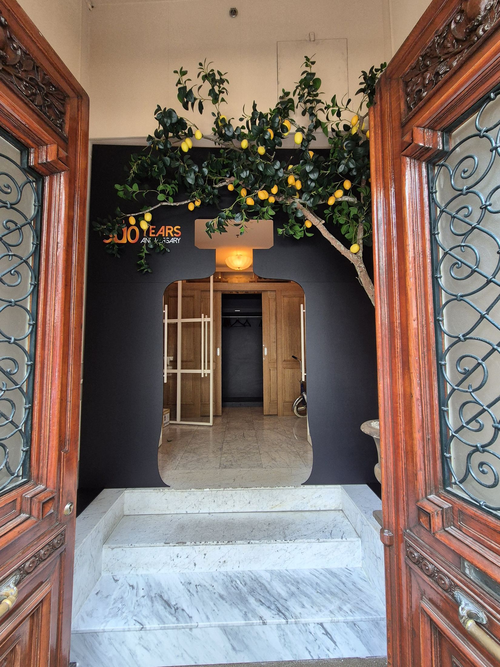 Bottle-shaped Disaronno entrance installation framed by carved wooden doors and a lemon tree