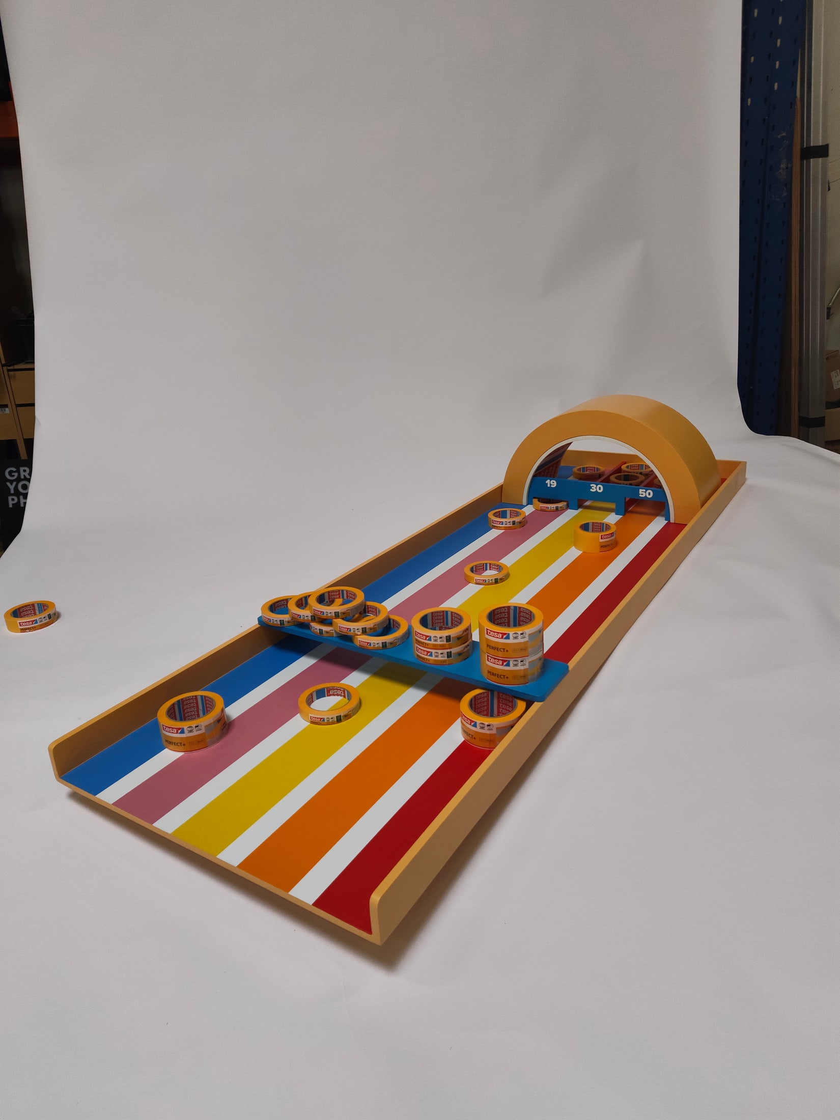 Angled player-eye view of the tape-roll pucks spread across the striped board