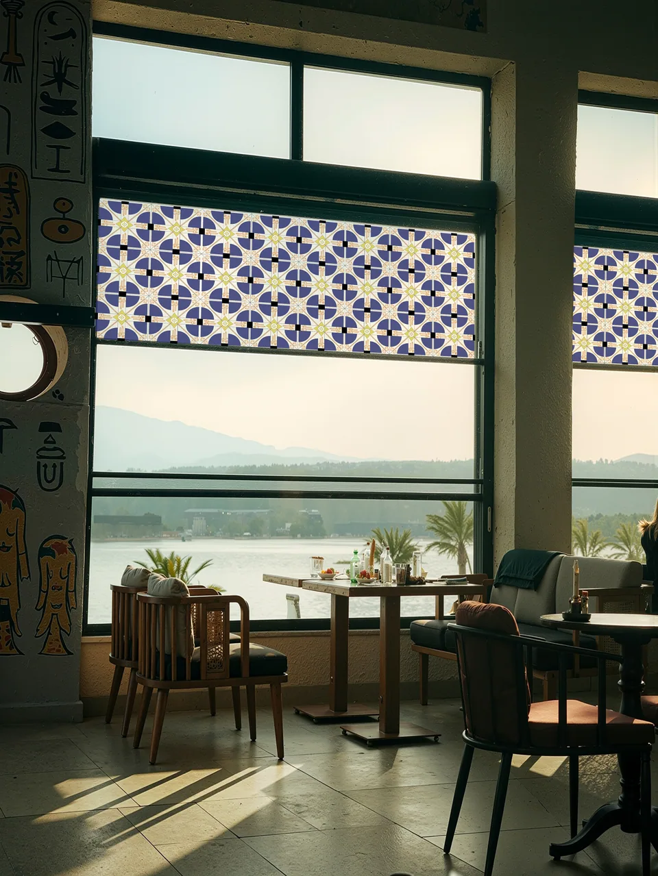 Between Lights installed across large windows, filtering sunlight through a repeating solar pattern