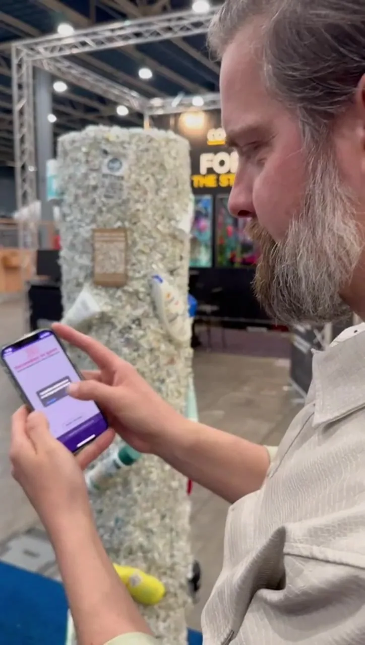 A visitor plays the Plastic Soup Foundation scanning game beside the recycled-plastic pole