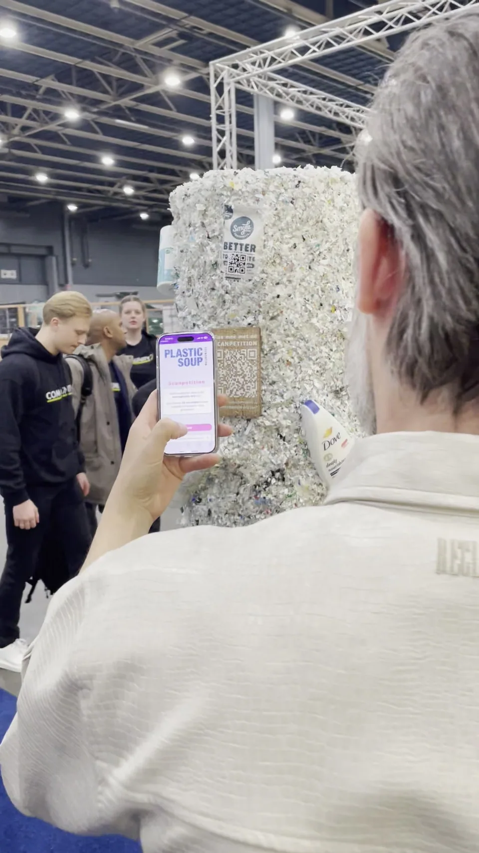A visitor holds the scanning game on a phone beside the recycled-plastic pole
