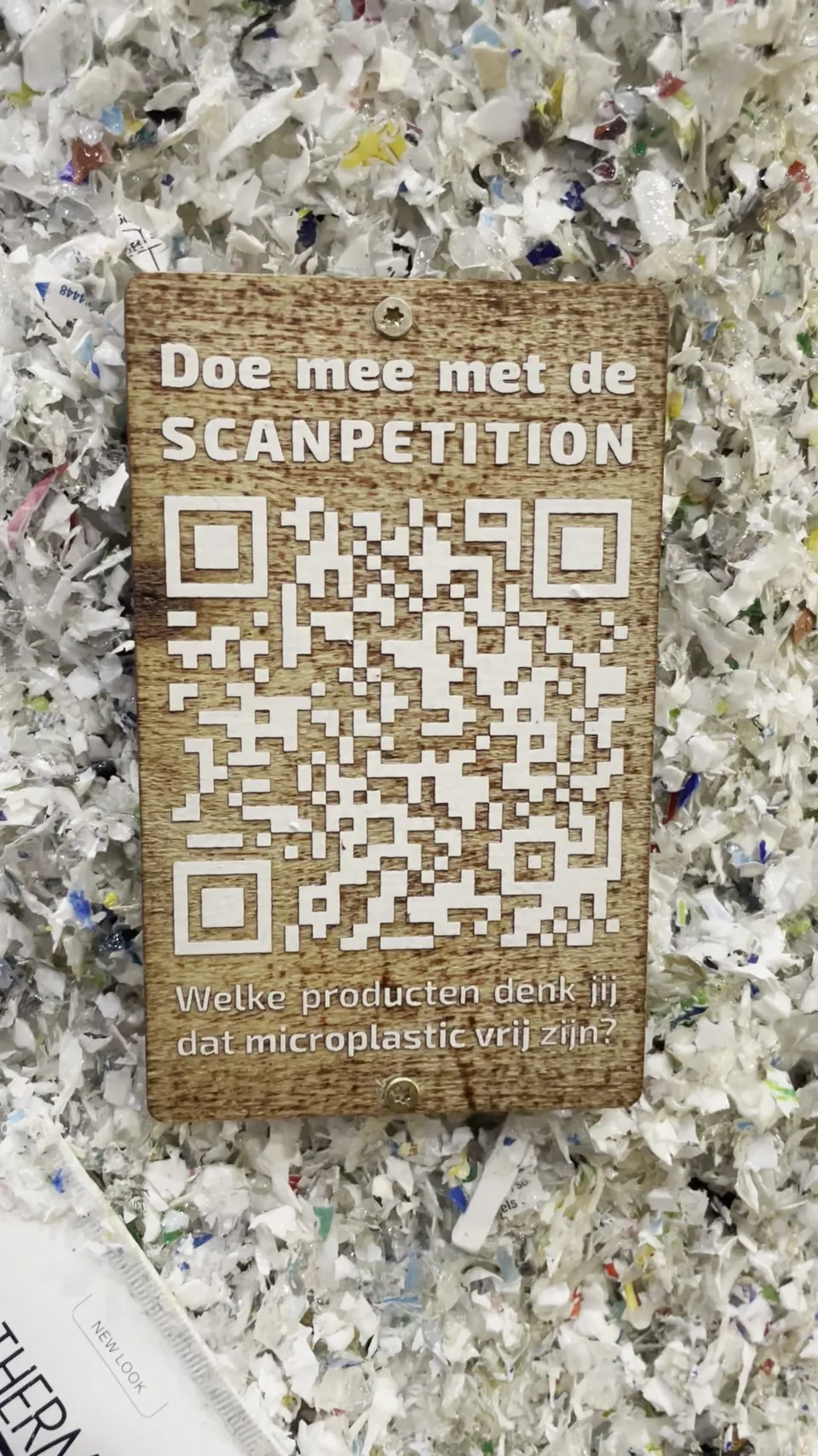 Wooden QR game sign fixed to the shredded-plastic surface of the installation