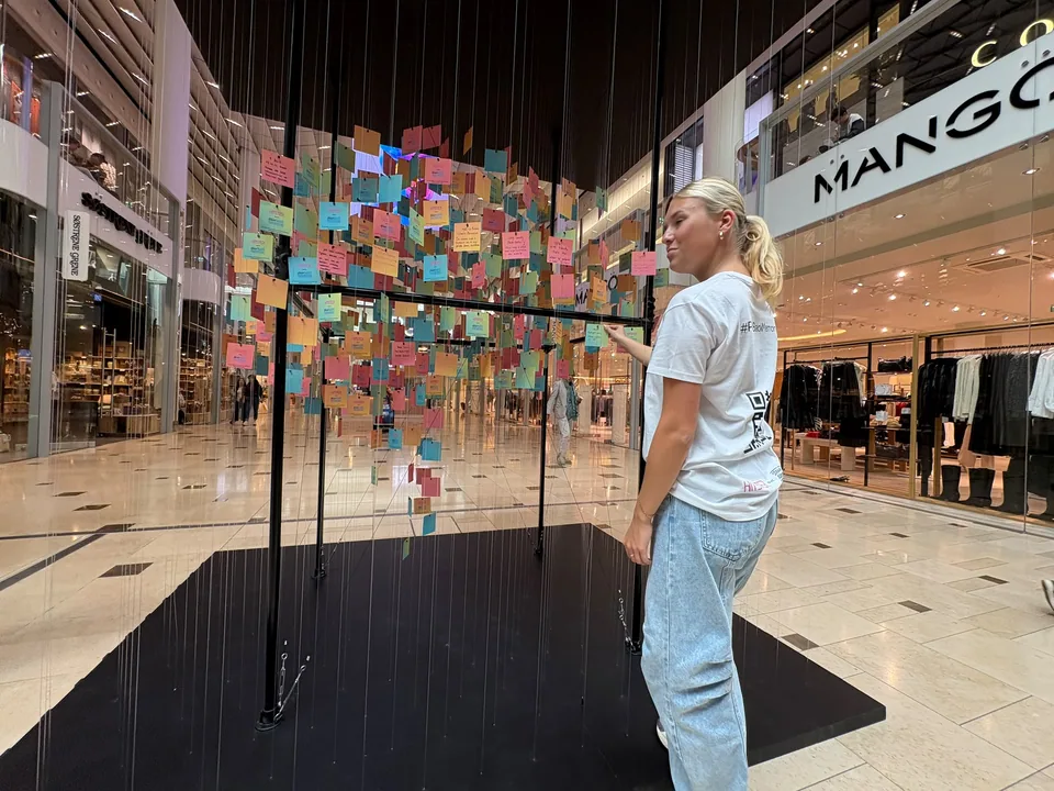 A visitor adding a card to the colourful brain-shaped installation
