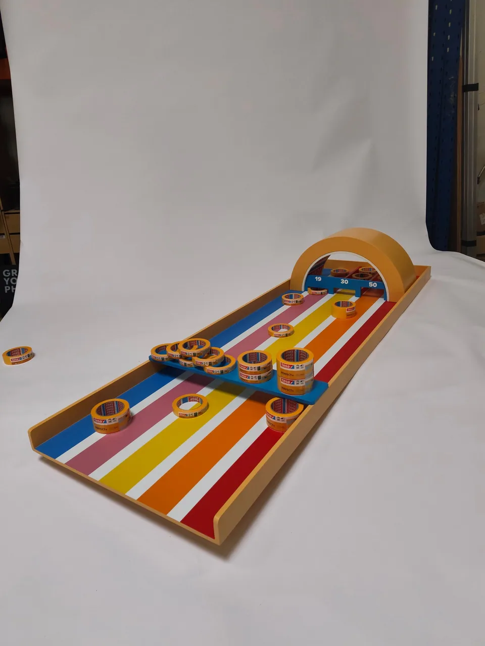 Angled player-eye view of the tape-roll pucks spread across the striped board